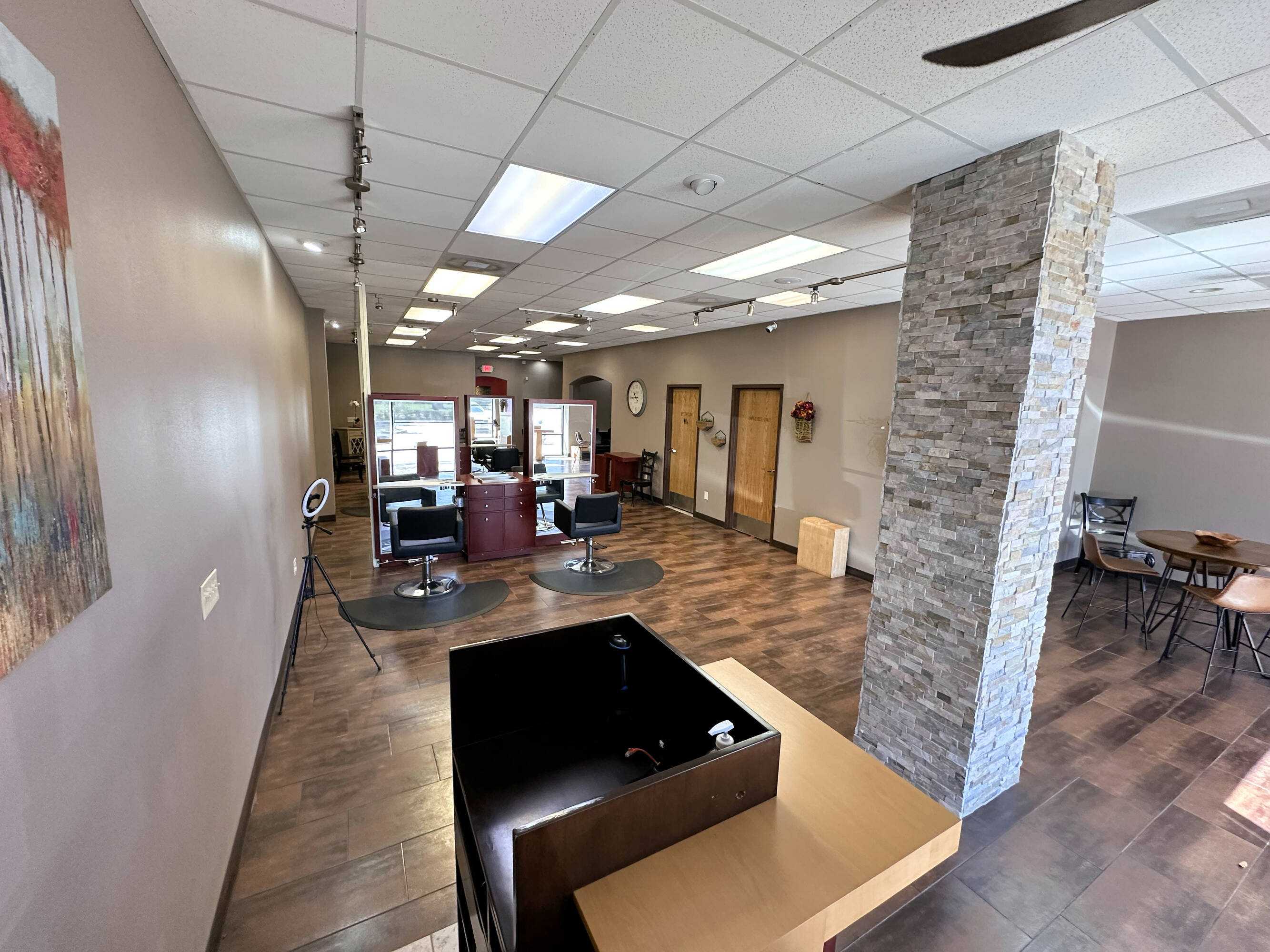 Interior view of a modern retail space with salon chairs, reception desk, and natural lighting.