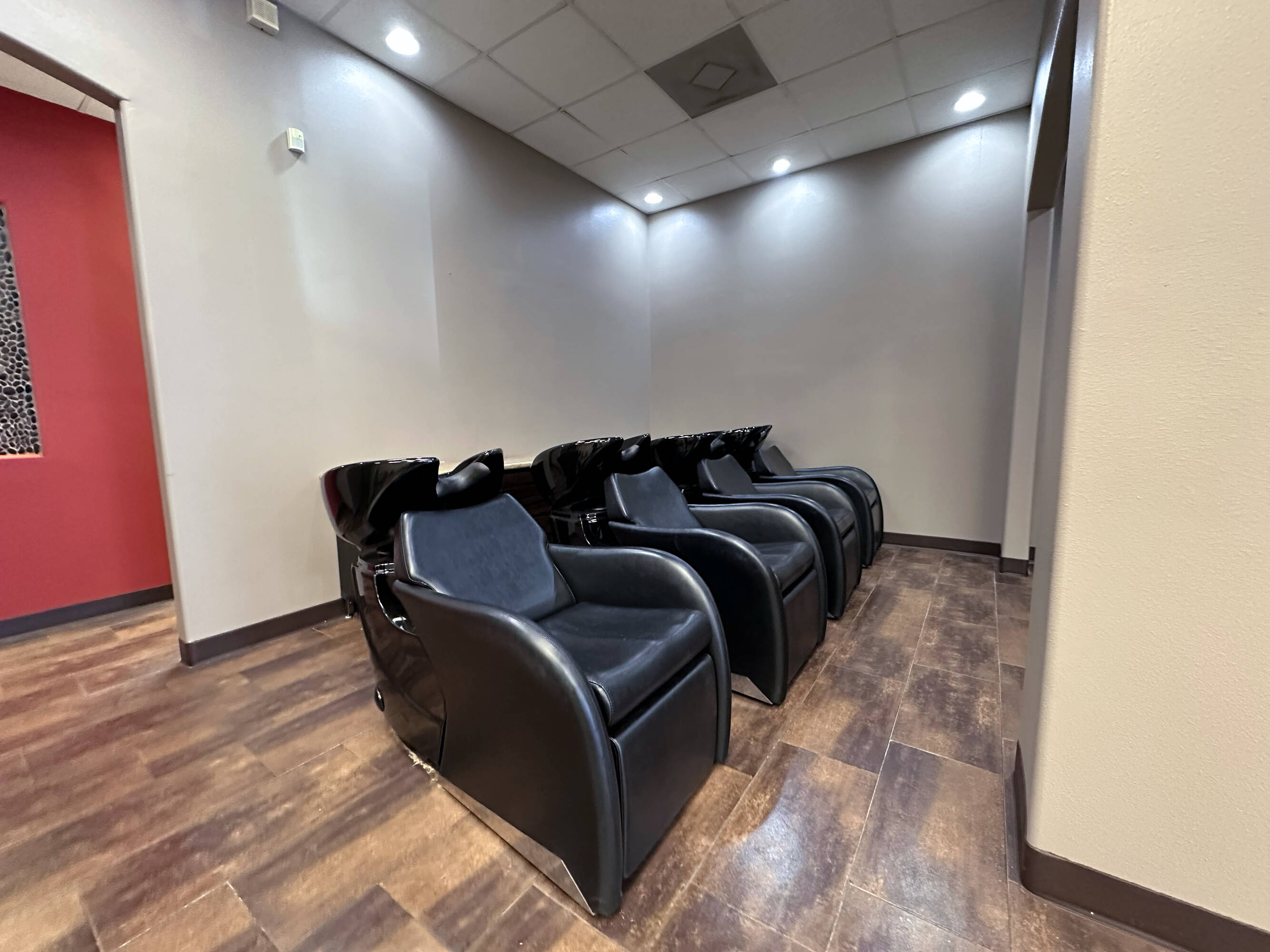 Four black salon chairs with integrated sinks in a well-lit room at Westheimer Parkway Retail Center.