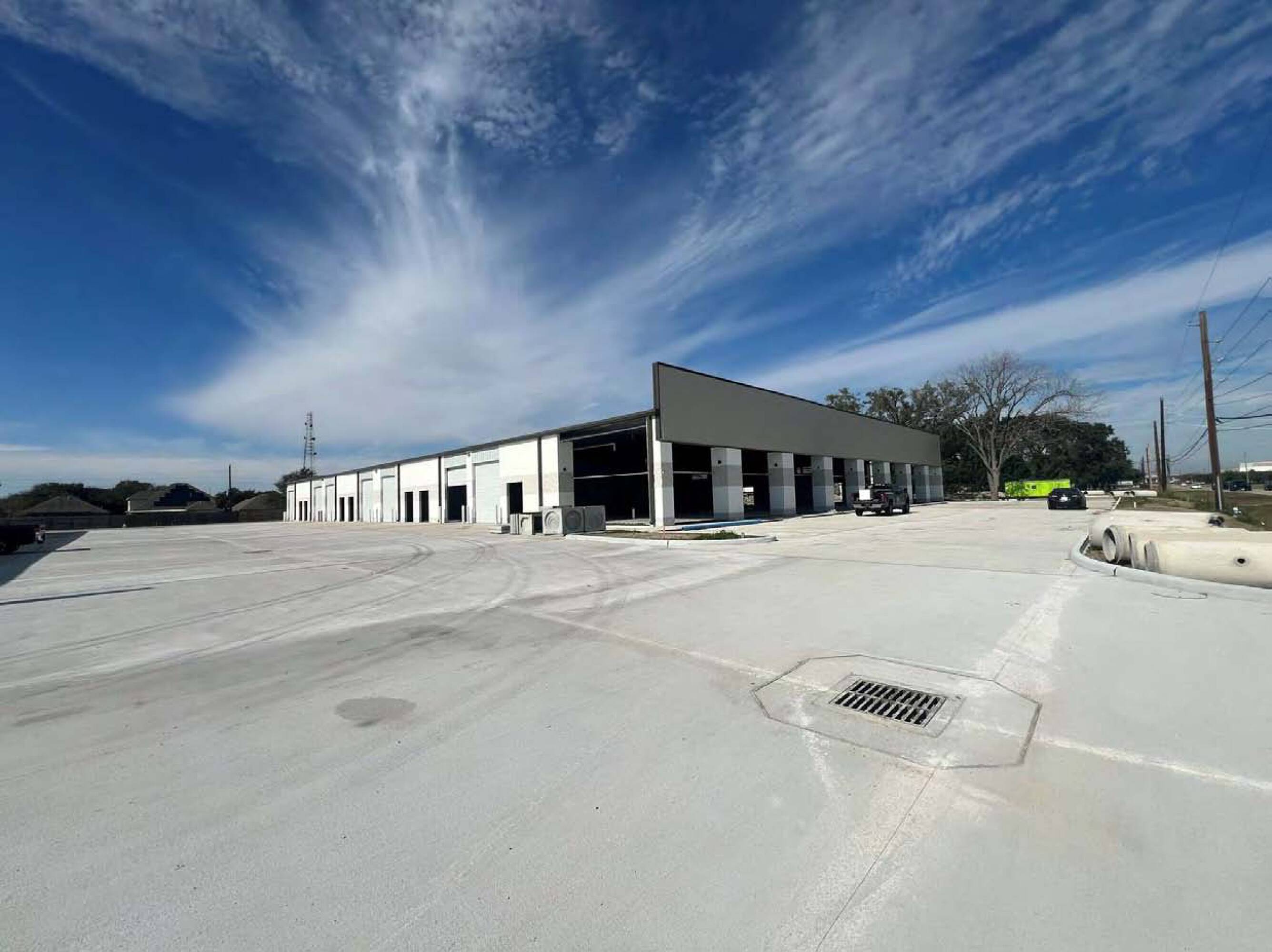 Exterior view of a modern industrial building at 8715 Jackrabbit Rd, Houston, TX, with ample parking and loading docks.