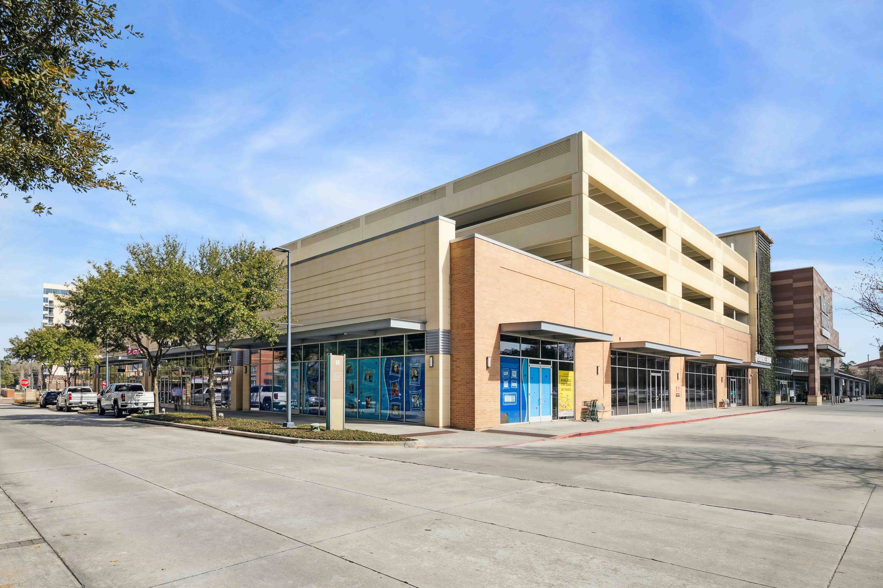 Hughes Landing on Lake Woodlands retail property with large windows and adjacent parking garage.